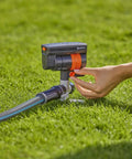 Hand adjusting ZoomMaxx Adjustable Oscillating Sprinkler On Metal Step Spike For Even Watering Of Large Lawns Up To 2300 Sq Ft With US Hose Threads And Quick Connects For Yard And Garden