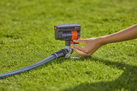Hand adjusting ZoomMaxx Adjustable Oscillating Sprinkler On Metal Step Spike For Even Watering Of Large Lawns Up To 2300 Sq Ft With US Hose Threads And Quick Connects For Yard And Garden