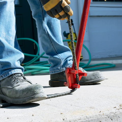 Manual steel rebar bending with the Marshalltown Qlt Manual Rebar Bender on concrete, showcasing 34-inch tool in use.