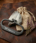 Flint And Steel Fire Starter Kit With Hand Forged Carbon Steel Striker, English Flint Stone, Jute Carry Bag on leather surface