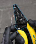 Gloved hands using Wire Stripper Tool For 8-16 Solid And 10-18 Stranded Wire With Precision Stripping Holes on a copper wire