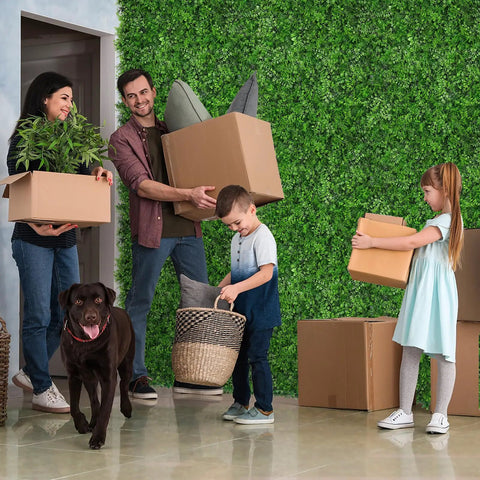 Family with boxes and dog in front of Artificial Hedge Wall Panels 20x20 Inch Boxwood Set, 12 Pieces, Easy Install Greenery Backdrop.