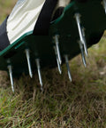 Close-up of Lawn Aerator Spike Shoes With Three Metal Buckle Straps Green Spiked Sandals penetrating grass for aeration