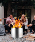 Heavy Duty 27 Inch Fire Pit Kit With 304 Stainless Steel Build in use during a backyard gathering with friends around a warm fire.