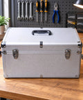 Heavy Duty Silver Metal Tool Box With Reinforced Corners Secure Carry Handle Tough As Nails For Workshop And Field Repair Jobs Keeps All Gear Locked And Loaded on a wooden workbench.