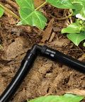 Close-up of elbow connector in 240 Piece Drip Irrigation Kit For Quarter Inch Tubing Includes Misting Nozzles Drippers Stakes Tees Elbows Plugs And More For Easy Diy Garden Irrigation System Upgrade among plants