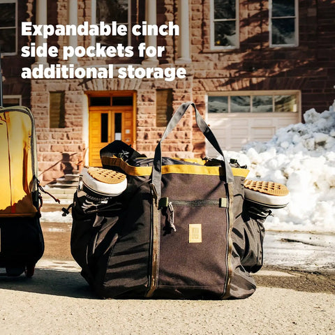 Monster 48L Gear Hauler Tote Bag In Recycled Nylon with ski boots in side pockets on snowy street.