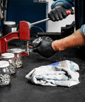 Mechanic using a tool in an auto shop with Recycled Multipurpose Industrial Wiping Cloths 49 Lb Pack Assorted Colors on workbench