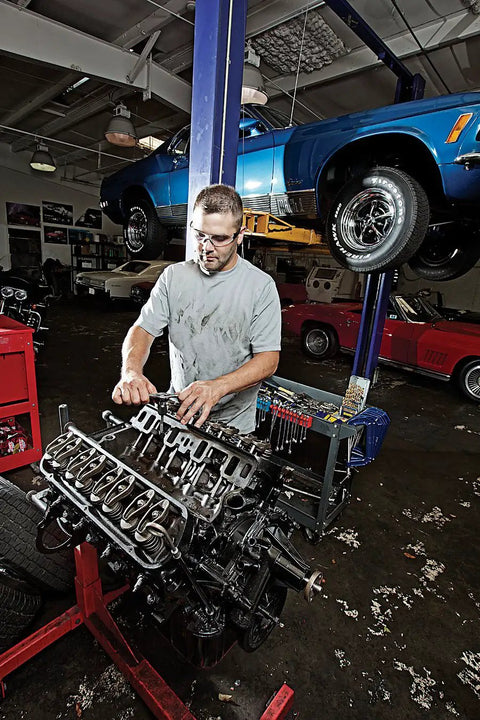 Mechanic working on car engine in a garage with cars on lifts