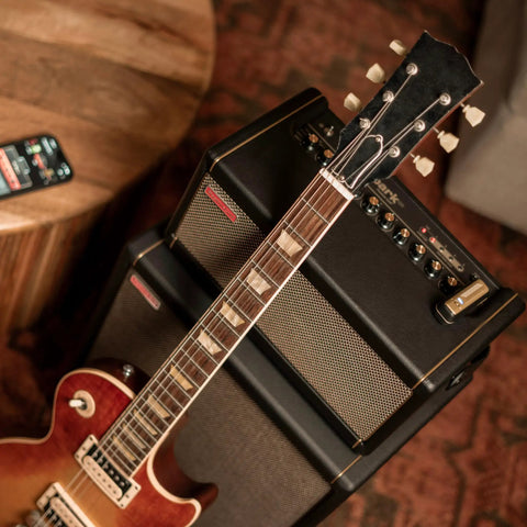 Wireless Guitar System With Rock-Solid 2.4G Transmission, 24-Bit/48kHz Audio on amplifier with electric guitar and smartphone.