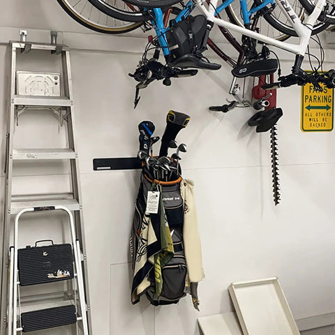Garage storage with 2 Pack Golf Bag Wall Mount Rack holding golf bags and clubs, bikes overhead, and ladder beside
