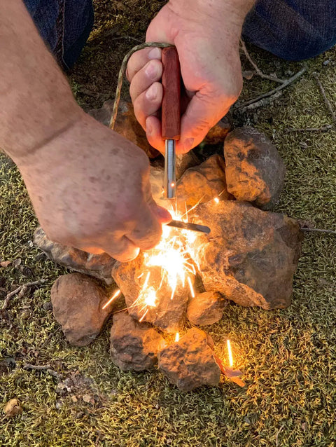 European Ferro Rod Fire Starter With Magnesium For Camping And Hiking being used over rocks to create sparks outdoors.