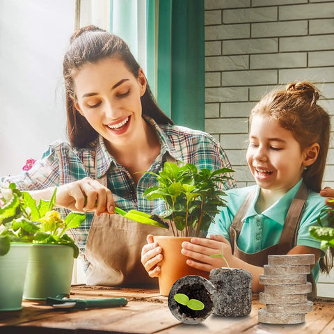 Mother and child planting with 50 Pack 35mm Seed Starter Peat Pellets for seedlings next to gardening tools on a table.