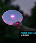 Person holding Flashflight LED Light Up Frisbee Rechargeable Flying Disc with Disc O Tech in dark, glowing with pink LED.