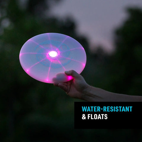 Person holding Flashflight LED Light Up Frisbee Rechargeable Flying Disc with Disc O Tech in dark, glowing with pink LED.