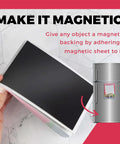 Hand holding a stack of non adhesive flexible magnetic sheets next to a fridge with a magnet in use. Pack Of 25 Non Adhesive Flexible Magnetic Sheets For Arts And Crafts, Easy To Cut 5 By 7 Inch 30 Mil Thick, Durable Plain Magnetic Sheets, Diy Friendly Magnetic Sheet Set For Projects And Classroom Use.