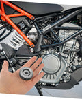 Hand holding gear above motorcycle engine illustrating Beefy 36 Tooth Motor Gear Set With Washers 3 Pcs Steel Gears for hubs