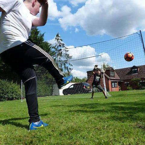 Children playing with a Backyard 3-In-1 Soccer Goal With Rebounder And Backstop Net For Solo Training And Team Practice in a yard.