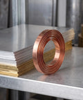 Straight Up Pure Copper Welding Strips For Ev Battery Packs And Power Modules Smooth Thin Copper Metal Roll on a flat metallic surface.
