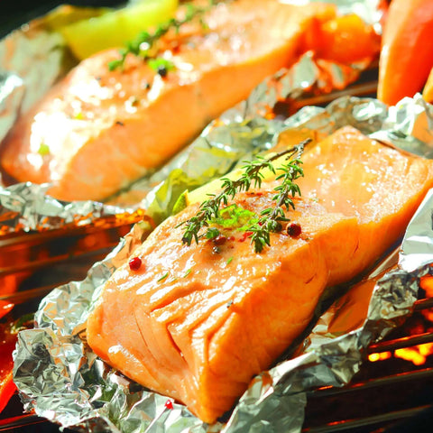 Grilling salmon on Premium Aluminum Foil Pop Up Sheets in Dispenser, showing heavy duty, food safe use for cooking in kitchen essentials.