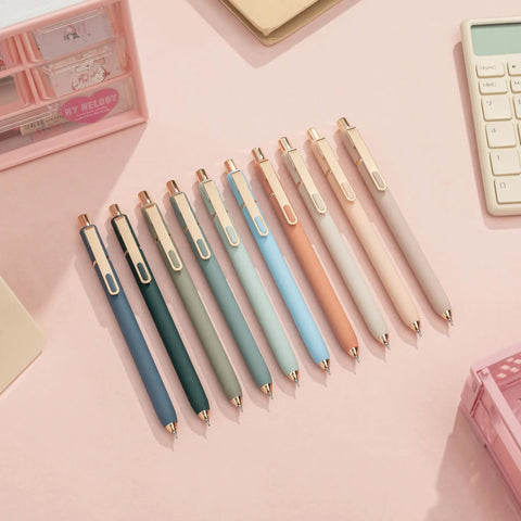 Assorted gel pens in various pastel colors with metal gold clips displayed on a desk.