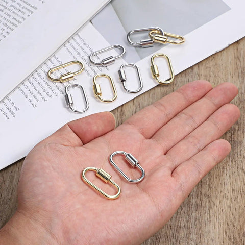 Hand holding gold and silver alloy 17x29 mm carabiners from Ten Pack Screw Carabiner Lock Charms For DIY Jewelry Making