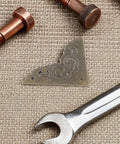 Retro Zinc Alloy Corner Guards 12 Piece Set For Boxes And Cabinets beside tools on textured surface