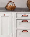 Antique Copper Cabinet Knobs 5 Pack One And A Quarter Inch Zinc Single Hole Center Pulls For Kitchen Cabinets And Drawers Vintage Retro Hardware Classic Rustic Cabinet Knobs For Home Renovation installed on white kitchen cabinets and drawers with basket and decor.