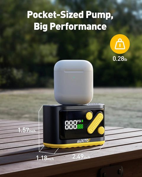 Black Mini Bike Pump With Gauge Auto Stop 120 Psi next to earbuds case, showing pocket size on wooden surface.
