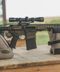 Tactical DeadShot Front And Rear Rifle Rest Combo Filled And Range Ready supports rifle on wooden surface outdoors.