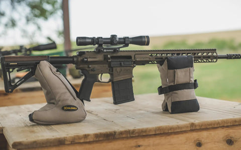 Tactical DeadShot Front And Rear Rifle Rest Combo Filled And Range Ready supports rifle on wooden surface outdoors.