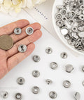 Hand holding components of 200 Pack Stainless Steel Snap Fastener Kit 15mm Heavy Duty Button Press Stud Caps For Marine Boats Canvas Leather Bags And DIY Crafts Ideal For Tent Covers Jackets Coats Vests Tops And More, spread on table.