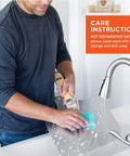 OUII aluminum pizza peel with wooden handle being washed under a kitchen faucet