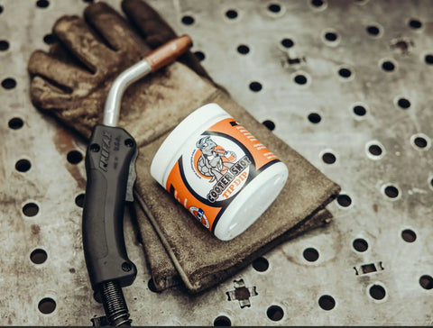 Tip Dip Anti Spatter Gel For Welding Nozzles Keeps Torch Tip Clean And Spatter Free For Mig TIG Arc Welders Non Flammable Silicon Free 16 Oz Works On Any Tip And Any Position on a workbench with welding gloves and torch
