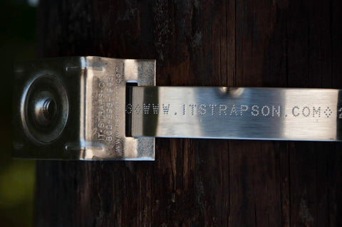 Stainless Steel Bull's Eye Sign Mounting Brackets With Straight Leg on wooden post, showing engraved website detail.