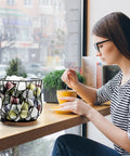 Woman enjoying coffee beside Go To Rustic Metal K Cup Pod Holder With Wooden Base Large Wire Basket on countertop