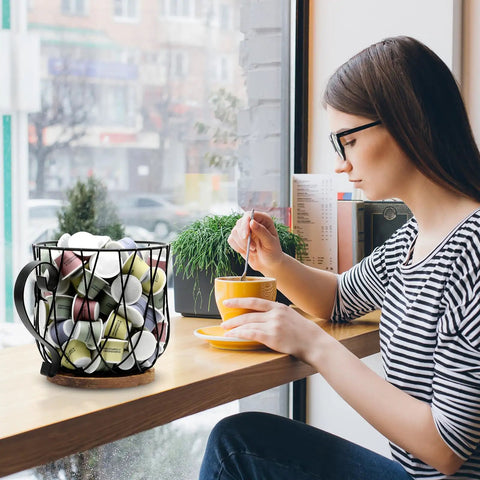 Woman enjoying coffee beside Go To Rustic Metal K Cup Pod Holder With Wooden Base Large Wire Basket on countertop
