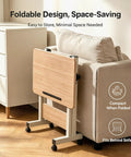 Rolling Laptop Standing Desk With Adjustable Tilting Tabletop And Smooth Locking Casters Lightweight Foldable Computer Workstation For Lowkey Work From Home Vibes In Compact Dorm Or Apartment Spaces folded beside a sofa.