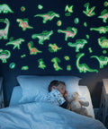 Child sleeping under glow in the dark dinosaur decals on wall