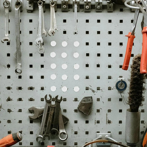 White Plastic Hole Plugs 100 Pack in use on metal pegboard among tools
