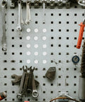 White Plastic Hole Plugs Set With Locking Screw Caps For Furniture And Office Installations on a pegboard with tools