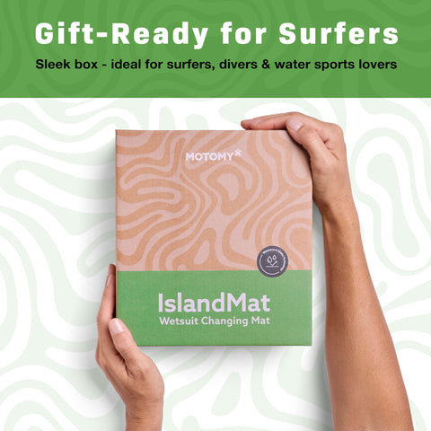 Hands holding a box of IslandMat Wetsuit Changing Mat, gift-ready for surfers, with text promoting 2 in 1 Gear Bag With 5000X Waterproof Tech.