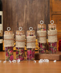 Five glass vials filled with dried rose petals, wrapped in burlap, with cork tops, displayed on a wooden surface.