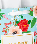Close-up of Extra Large Mothers Day Gift Bag With Tissue Paper in bright blue with red roses and green foliage design.