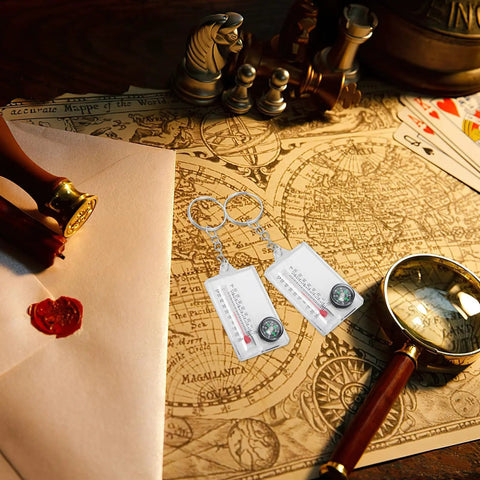 Two Pack Portable Keychain Compass With Thermometer Wear Resistant Mini Pocket Navigator on vintage map with seal and magnifier.