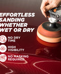 Handheld orbital polisher with orange buffing pad on a red car body panel