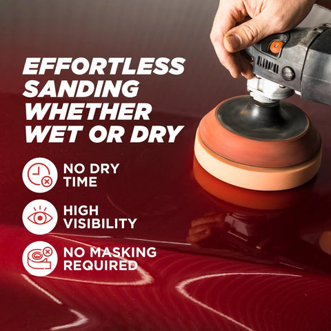 Handheld orbital polisher with orange buffing pad on a red car body panel