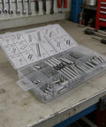 Grab Your Ultimate 200 Pcs Tension Compression Spring Assortment Kit With Organized Box For Automotive Repair, Tool Maintenance, And DIY Projects Featuring 20 Sizes Of Heavy Duty Metal Extension Coil Springs. Organized clear plastic box with metal tension and compression springs on a workshop bench