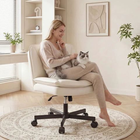 Woman sitting on Criss Cross Legged Swivel Office Chair With Wheels, Armless Wide Vanity Desk Chair In Scratch Resistant PU Leather, Thick Two Layer Cushion For All Day Comfort, Ideal For Home Office Or Bedroom, Beige, holding a cat.