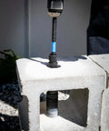 Spyder 12-inch dual-hex locking hole saw extension chuck on a drill with blue band, drilling into concrete block.